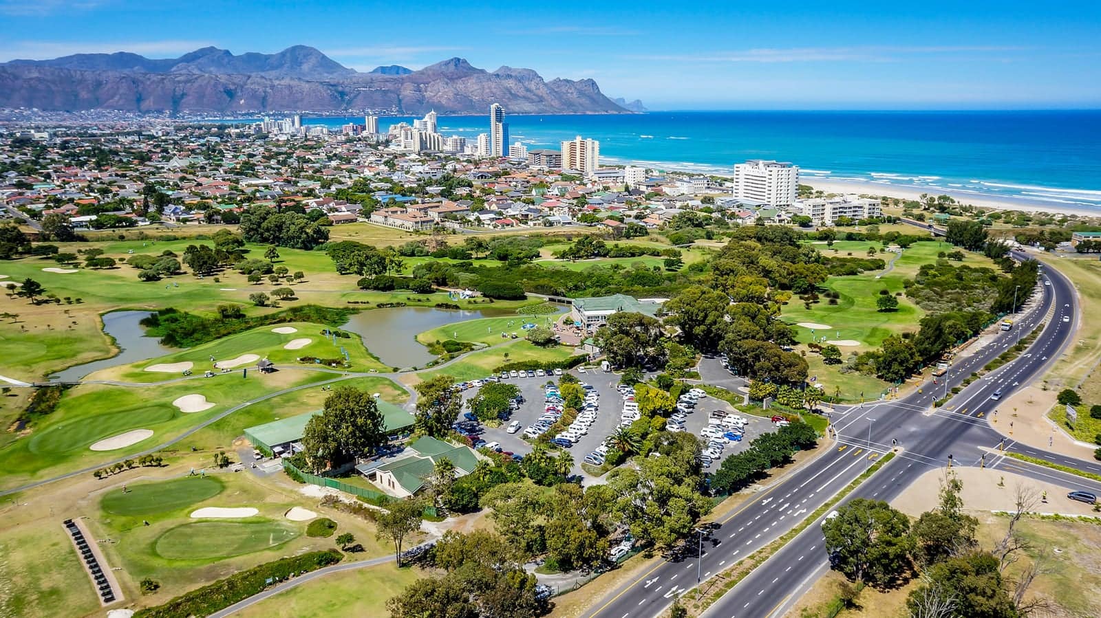 Strand from the air, with the golf course, the town and the beachfront towers below the mountains