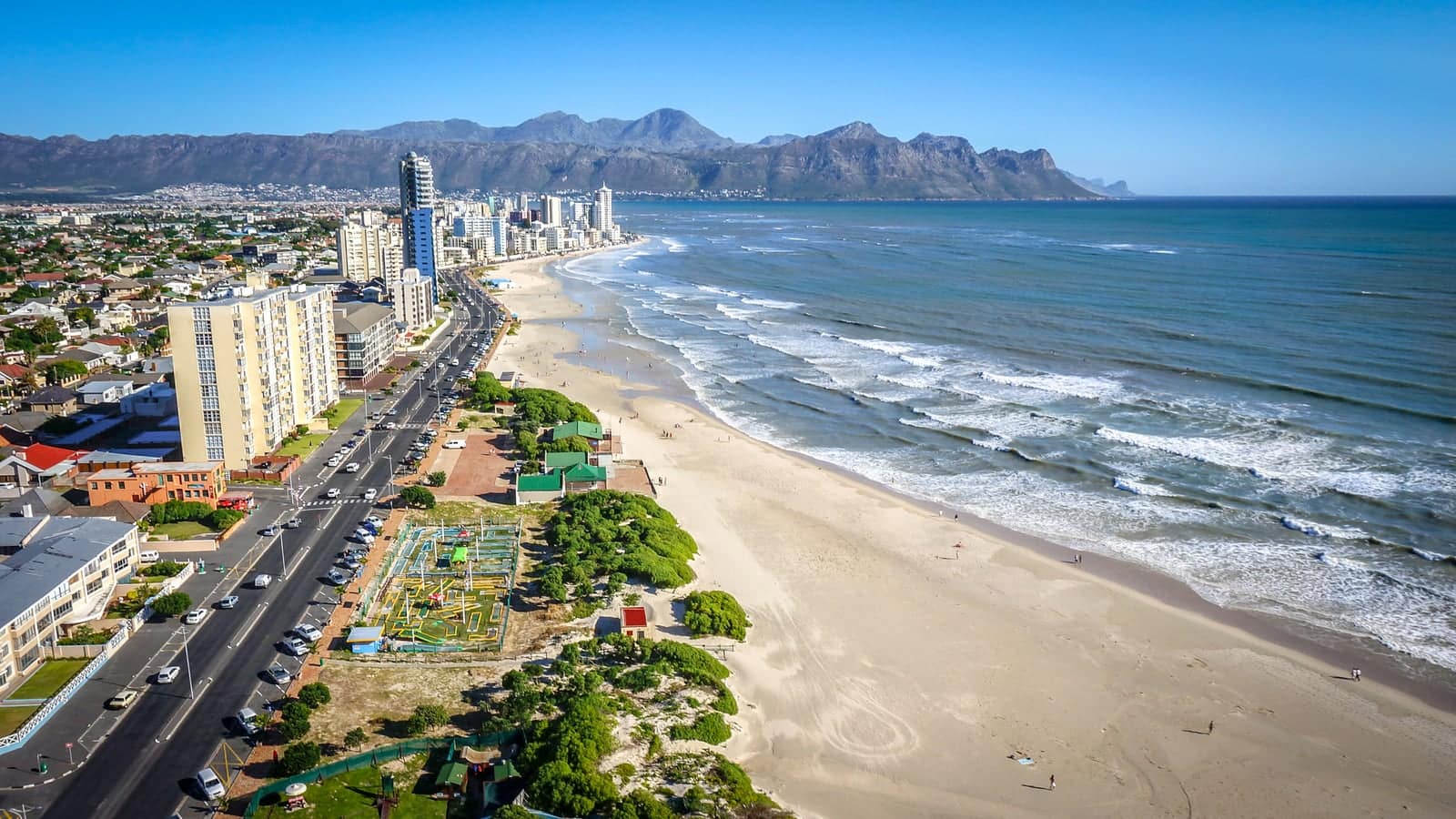 Strand beachfront from the air, with Beach Road, the promenade and the beach curving towards the mountains